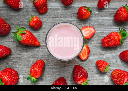 Strawberry Smoothie oder Milchshake in einem Glas mit frischen Beeren auf rustikalen Holzmöbeln Hintergrund. gesunde Ernährung. nach oben anzeigen. Soft Focus Stockfoto