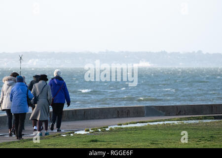 Eine Gruppe von älteren Menschen, einen Spaziergang am Meer entlang an einem sehr windigen Tag Stockfoto