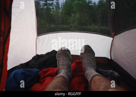 Man entspannende mit Wolle Socken beim Camping in einem Zelt in den Adirondack Mountains Stockfoto