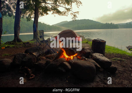 Adirondack Camping mit Lagerfeuer, Zelt Zuflucht auf einem Bergsee im Sommer. Sommer bushcraft Camping in Upstate New York. Stockfoto