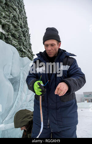 Elektriker reinigt die Enden des Kabels das Eis Figuren zu beleuchten Stockfoto