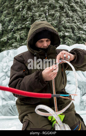 Elektriker reinigt die Enden des Kabels das Eis Figuren zu beleuchten Stockfoto