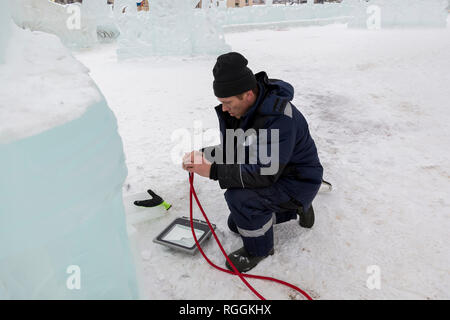 Elektriker reinigt die Enden des Kabels das Eis Figuren zu beleuchten Stockfoto