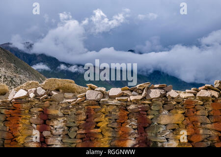 Karge Berglandschaft mit einem bunten Mani Mauer im oberen Mustang, dunkle Monsunwolken anfahren Stockfoto