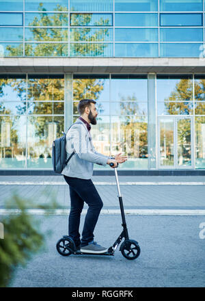 Geschäftsmann mit Roller auf dem Weg Stockfoto