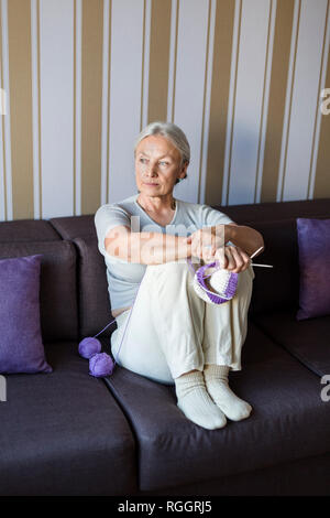 Portrait von nachdenklich ältere Frau sitzt auf der Couch mit Stricken auf Distanz suchen Stockfoto