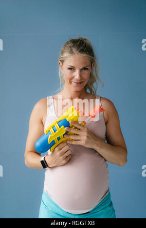 Portrait von lächelnden schwangere Frau mit Wasserpistole Stockfoto