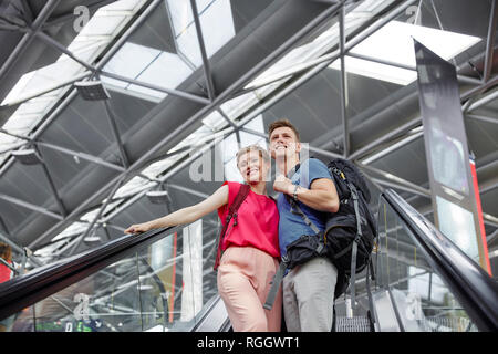 Glückliches Paar auf der Rolltreppe am Flughafen Stockfoto