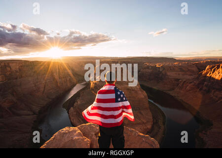 USA, Arizona, Colorado River, Horseshoe Bend, junger Mann auf Sicht mit amerikanischer Flagge Stockfoto