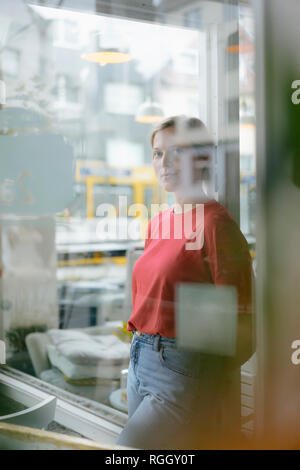 Porträt der jungen Frau lehnte sich gegen französische Tür in einem Cafe Stockfoto