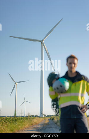 Verschwommene Sicht der Techniker stehen auf Feld Pfad in einen Windpark mit Kletterausrüstung Stockfoto