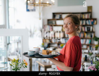 Portrait von lächelnden jungen Frau mit Kaffee und Kuchen in einem Cafe Stockfoto