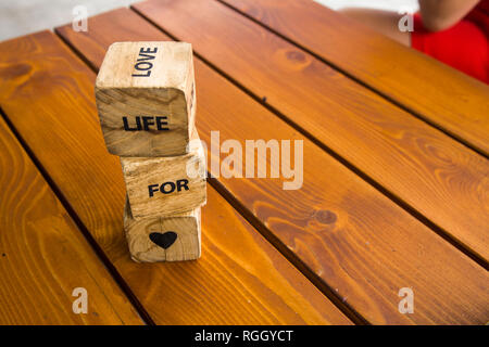 Holzblöcke mit den Worten liegen auf dem Tisch. Holzwürfel mit Buchstaben und Symbolen. Leben für die Liebe. Stockfoto