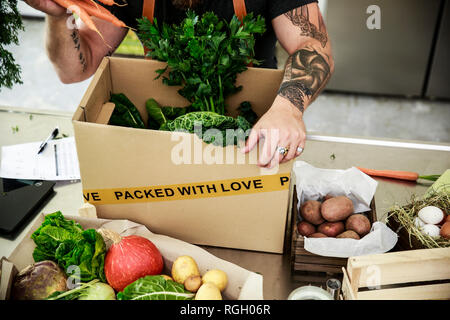 Reifer Mann mit Lieferservice Verpackung Bio Gemüse in Kartons Stockfoto