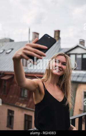 Portrait von lächelnden blonde Frau, die selfie auf der Dachterrasse Stockfoto