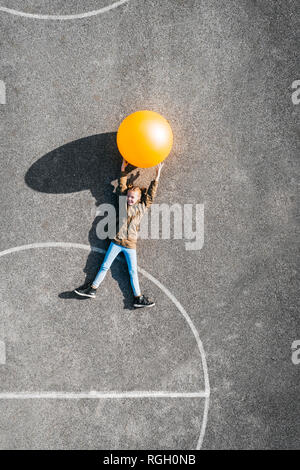 Österreich, Luftaufnahme von Basketballplatz, Mädchen mit großen Ball auf dem Boden liegend Stockfoto