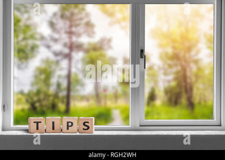 Tipps Zeichen in einem Fenster mit Blick auf einen grünen Garten mit hohen Bäumen im Sonnenlicht Stockfoto