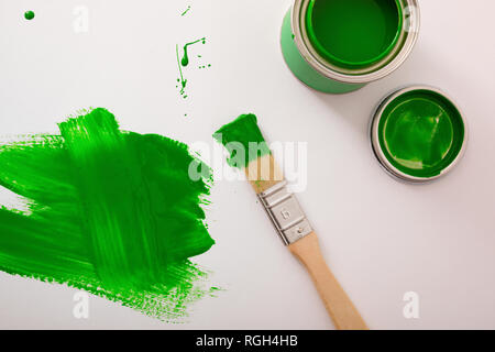 Grüne Acrylfarbe Kanister auf weißen Tisch mit Pinsel gemalt. Horizontale Komposition. Ansicht von oben. Stockfoto