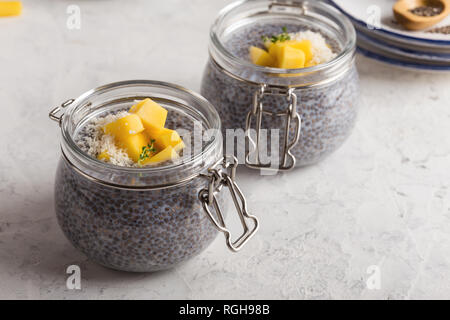 Mango chia Dessert mit der Milch in Glas, veganen Snack oder Dessert auf hellgrauen Hintergrund, gesunde Ernährung Stockfoto