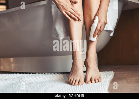 Weibliche Beine. Junge Frau im Badezimmer, ihre Beine streicheln. Stockfoto