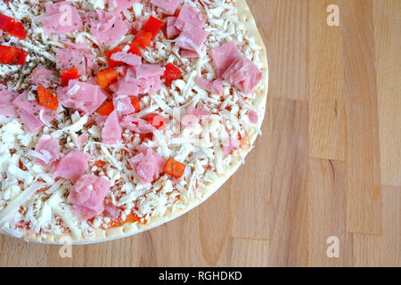 Teil bereit, appetitliche Pizza mit Speck und Käse und Gemüse auf runden Platte auf Sandy braun Küche aus Holz Tisch Top View close-up Stockfoto