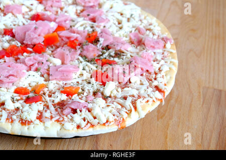 Teil bereit, appetitliche Pizza mit Speck und Käse und Gemüse auf runden Platte auf Sandy braun Küche aus Holz Tisch Top View close-up Stockfoto