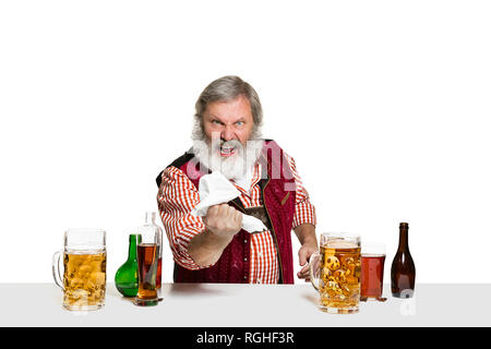 Das Senior Expert männlich Barkeeper mit Bier im Studio auf weißem Hintergrund. Internationale Barkeeper Tag, Bar, Alkohol, Restaurant, Bier, Party, Pub, St. Patrick's Day Celebration Konzept Stockfoto