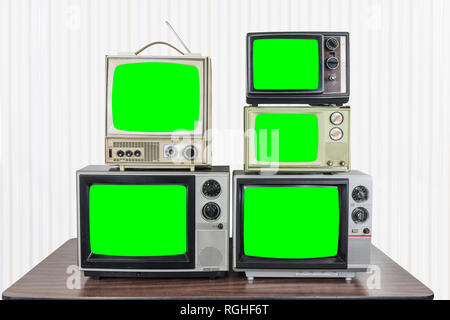 Fünf vintage Fernseher auf alten Holztisch mit Chroma Key Green Screens Stockfoto
