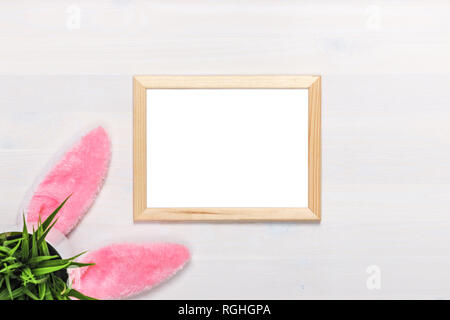 Rahmen liegen auf einem weißen Hintergrund Holz, Hase Ohren, einen Blumentopf mit künstlichen grünen Gras. Ostern Konzept. Kopieren Sie Platz. Stockfoto