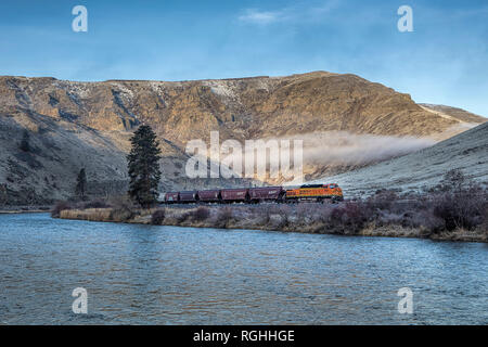 Ein Güterzug fährt durch eine Schlucht von der Yakima Fluss in Washington. Stockfoto