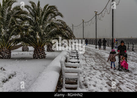 Menschen kämpfen mit dem Schnee und eisigen Bedingungen beim Spaziergang entlang der Strandpromenade von Torquay während der "Tier aus dem Osten' Sturm im März 2018. Stockfoto