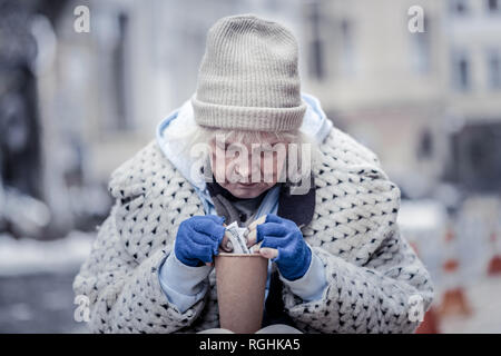 Nette obdachlose Frau unter hundert Dollar Banknote Stockfoto