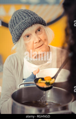 Traurig freudlos Frau bittet um die Suppe Stockfoto