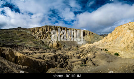 Panoramablick auf die Luftaufnahme auf die karge Landschaft des Oberen Mustang, interessant geformte Felswand mit künstlichen Grotten in der Ferne Stockfoto