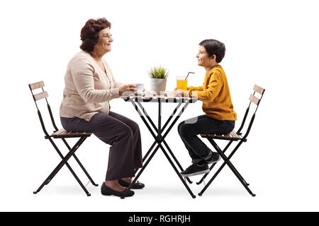 Die volle Länge der Großmutter an einem Tisch sitzt und spricht zu ihr Enkel auf weißem Hintergrund Stockfoto