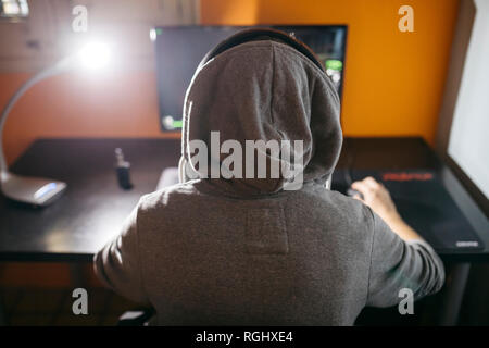 Junge Mann an seinem PC sitzen, Spielen von Computerspielen Stockfoto