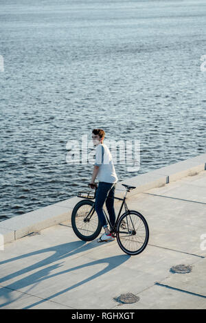 Junger Mann mit Pendler fixie Bike eine Pause am Flußufer Stockfoto