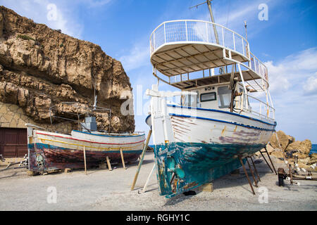 Alte Fischerboote am Ufer. Schiffe an Land gezogen. Hafen in der Ortschaft Hersonissos auf der Insel Kreta, Griechenland. Stockfoto