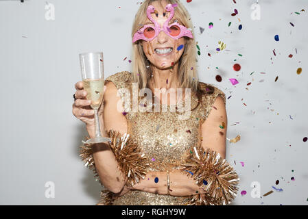 Ältere Frau mit goldenen Kleid und flmingo geformte Gläser, celebtraing Silvester Stockfoto