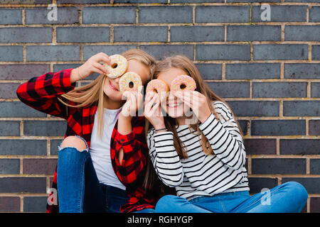 Zwei Mädchen Spaß mit Donuts Stockfoto