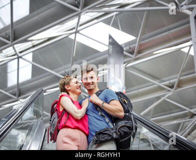 Glückliches Paar auf der Rolltreppe am Flughafen Stockfoto