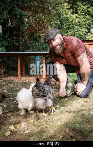 Mann in seinem eigenen Garten, mann Fütterung freie Hühner Stockfoto