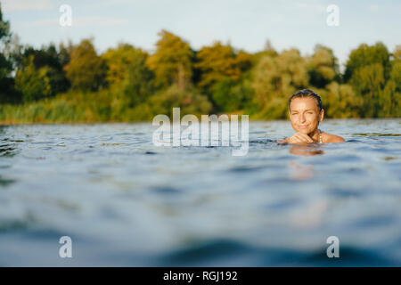 Porträt der lächelnde Frau schwimmen in einem See Stockfoto