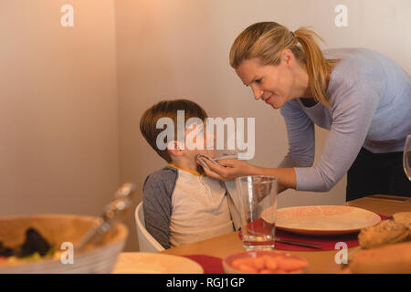 Seitenansicht von Mutter abwischen Söhne den Mund mit einer Serviette am Esstisch zu Hause Stockfoto