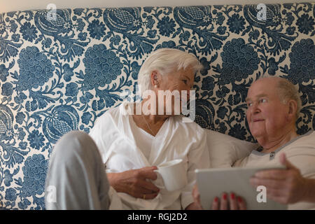 Vorderansicht des Senior Paar mit digitalen Tablet, Trinken und suchen sich im Bett zu Hause Stockfoto