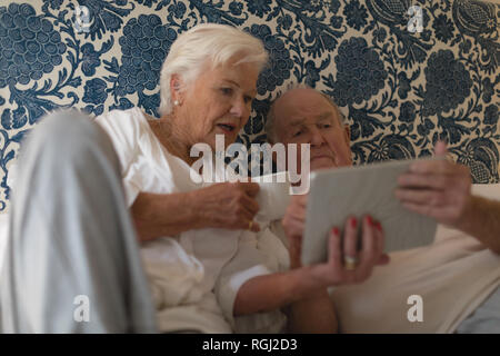 Vorderansicht des Senior Paar mit digitalen Tablet und Trinken im Bett zu Hause Stockfoto