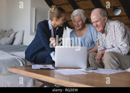 Vorderansicht eines weiblichen Arzt und Senior paar Suchen und Diskutieren über Laptop zu Hause Stockfoto