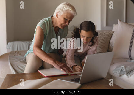 Vorderansicht eines Großmutter ihrer Enkelin helfen bei Hausaufgaben im Wohnzimmer zu Hause Stockfoto