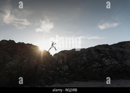 Frankreich, Bretagne, junger Mann auf einem Felsen bei Sonnenuntergang springen Stockfoto