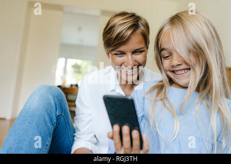 Glückliche Mutter und Tochter an Smartphone suchen zusammen Stockfoto